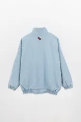 Campera estilo olímpica de jean celeste con recortes geométricos blancos.