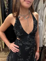 Vestido corto de lentejuelas color verde oliva, con escote en V, breteles finos cruzados en la espalda, cut-outs laterales y volado en el ruedo.