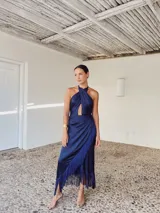 Vestido largo azul con escote halter cruzado, abertura en el pecho, falda drapeada con flecos y corte irregular.