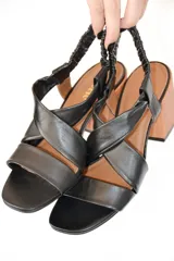 Sandalias negras de cuero con tiras cruzadas y talón elástico fruncido. Taco de madera de 7,5 cm y punta cuadrada.