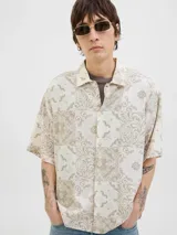 Camisa de manga corta con estampado de cachemira en tonos beige y blanco, cuello resort y cierre de botones. Confeccionada en tejido plano con mezcla de algodón y lino, de corte amplio.