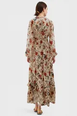 Vestido largo de gasa color beige con estampado floral en tonos rojos y verdes, escote en V con lazo y mangas largas abullonadas.