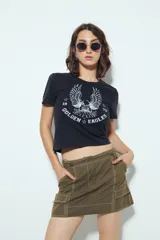 Falda corta tipo cargo de tiro medio, color negro, con costuras visibles en contraste blanco y bolsillos aplicados.