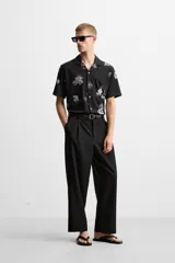 Camisa negra con estampado floral en tonos grises, de manga corta y cuello bowling.