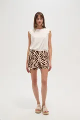 Short de lino color beige, de tiro alto y corte holgado, con bolsillos laterales y cierre frontal con botón y cremallera.