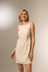 Vestido corto color beige, de algodón, con escote cuadrado y tirantes finos ajustables. Presenta aberturas laterales con detalle de estampado animal print.