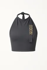 Top gris de cuello alto y espalda descubierta, sin costuras y con detalle de logo metálico dorado en el frente.