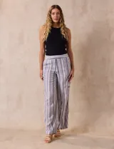 Pantalón de lino a rayas verticales en tonos beige, azul y blanco. Tiene pretina elastizada, bolsillos inclinados delanteros y bolsillo lateral tipo cargo.