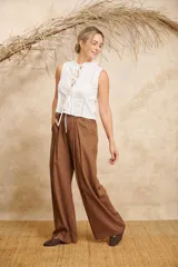 Pantalón ancho color beige de lino con cinto y pretina con elástico en la parte de atrás.