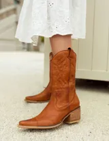 Botas texanas blancas de cuero con caña media, punta fina y cierre lateral. Presentan costuras decorativas en el empeine y el contorno de la caña.