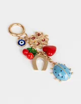 Llavero metálico dorado con dije de mosquetón y charms colgantes: ojo turco, trébol de cuatro hojas con la palabra "LUCK", cerezas, herradura, corazón rojo y mariquita celeste con lunares negros.