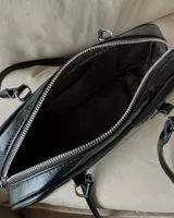 Cartera baguette negra de cuero sintético con doble asa corta y cierre superior con cremallera.