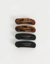 Set de cuatro hebillas para el pelo, dos color carey y dos color negro. Cada hebilla tiene forma rectangular redondeada con una abertura central.
