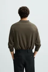 Polo de manga larga color negro, tejido en hilatura con mezcla de algodón y seda, de corte regular fit, con cuello solapa y cierre frontal de botonadura.