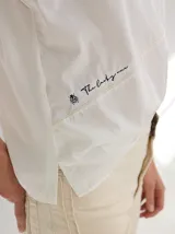 Remera blanca de algodón con corte holgado y costuras a la vista en color beige.