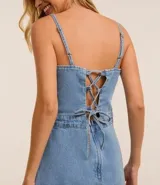 Enterito corto de jeans celeste, con breteles finos, escote cuadrado, lazo en la espalda y ruedo doblado.