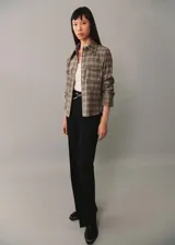 Camisa marrón a cuadros con cuello camisero, dos bolsillos de parche en el pecho, manga larga con puños abotonados y cierre frontal con botones.