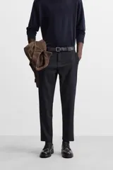 Pantalón slim fit negro confeccionado en tejido con elasticidad en ambas direcciones. Cuenta con bolsillos frontales y traseros de vivo con botón. Cierre frontal con cremallera y botón.