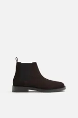 Bota Chelsea de cuero marrón oscuro con elásticos laterales negros, tirador trasero y suela plana.
