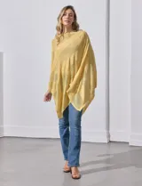 Poncho blanco de tejido calado con lurex, terminación asimétrica y cuello redondo.