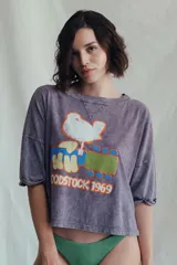 Remera de algodón color lavanda con estampado vintage de un pájaro sobre una guitarra y la inscripción "Woodstock 1969".