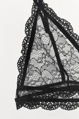 Bralette triangular semitransparente negro con tirantes finos ajustables y aplicación de encaje floral a tono. Cierre en espalda con gancho metálico.