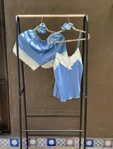 Pijama de satén elastizado color champagne, compuesto por musculosa con escote en V y detalle de puntilla elastizada, y short con elástico en la cintura y terminación con puntilla.