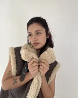 Chaleco marrón de cuero ecológico con interior de corderito color beige. Cierre con botones a presión.