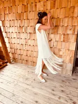 Vestido tejido color blanco con hilo metalizado, corte oversized, mangas cortas y flecos en el ruedo.