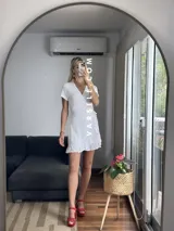 Vestido corto rojo con escote cruzado, mangas cortas y falda con volados. Se ajusta con lazo lateral tipo pareo.