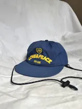 Gorra de béisbol azul marino con visera curva y bordado frontal en amarillo que dice "LOVE & PEACE" y debajo "PP:ONE".
