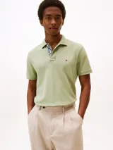 Chomba verde claro de corte regular, confeccionada en tejido piqué de algodón orgánico con un toque de elastano. Tiene cuello tipo chomba, cartera de dos botones y logo de Tommy Hilfiger bordado en el pecho.