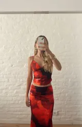 Conjunto de top corto con breteles finos y falda larga ajustada, ambos con estampado floral en tonos rojo y negro.