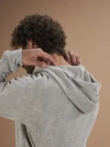 Campera con capucha de toalla color gris claro, con cierre completo y bolsillos frontales.