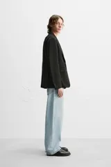Blazer negro de corte regular fit, confeccionado en tejido con viscosa. Presenta cuello con solapas de muesca, manga larga con puños abotonados, bolsillo de vivo en el pecho, bolsillos de solapa en la cadera, bolsillo interior, aberturas en la espalda y cierre frontal con dos botones.
