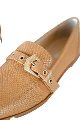 Mocasines color camel con textura símil piel de reptil y detalle de hebilla dorada.