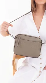 Bandolera color beige con diseño geométrico en el frente, cierre superior y correa larga regulable.