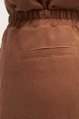 Pantalón de lino color marrón, de corte recto y tiro alto, con cintura elástica y bolsillos laterales.