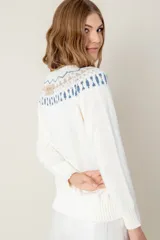 Sweater tejido color verde agua con cuello redondo y diseño de ochos con detalles rosados en la parte superior.