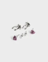Set de tres pares de aros pasantes con cierre de tope a presión: un par de aros con forma de rosa color rojo óxido, un par de aros con forma de moño plateado y un par de aros con forma de perla blanca.