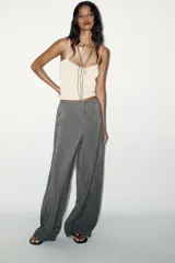 Pantalón palazzo color gris topo de tejido fluido, con cintura elástica ajustable con cordones y bolsillos laterales.