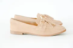 Mocasín de gamuza color crema, con detalles de costura y flecos en la parte delantera, ideal para un look sofisticado.