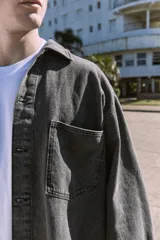 Camisa de denim negra de manga larga con cuello clásico y cierre con botones. Diseño amplio con bolsillos en el pecho.