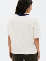 Remera color beige con cuello redondo azul marino y estampa geométrica en el frente con la inscripción "Athletic Club 1880".