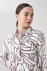 Camisa de lino color blanco con estampa abstracta color chocolate, de manga larga y cuello clásico.