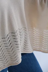 Poncho de tejido de punto color crudo, con escote en V y detalle calado en el ruedo.
