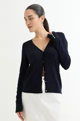 Cárdigan negro de tejido de punto fino con escote en V, cierre frontal con botones dorados y mangas largas con puños ajustados.