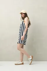 Vestido de algodón sin mangas, de corte recto y largo por encima de la rodilla, con diseño a rayas horizontales y verticales en tonos beige y blanco.