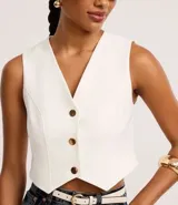 Chaleco color crema con escote en V y abotonadura frontal con botones dorados. Corte slim.