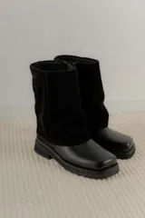Bota de cuero negra con diseño moderno y suela gruesa.
